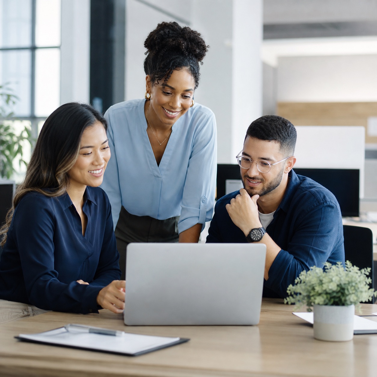 Professionals collaborating around a laptop in a modern office